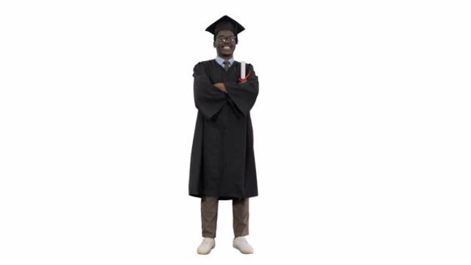 毕业长袍折叠手臂的非裔美国男学生在白色背景上对着相机露出灿烂的笑容