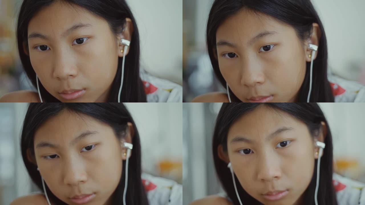 快乐的亚洲女孩使用耳塞和智能手机观看病毒视频，同时在家放松，生活方式概念。