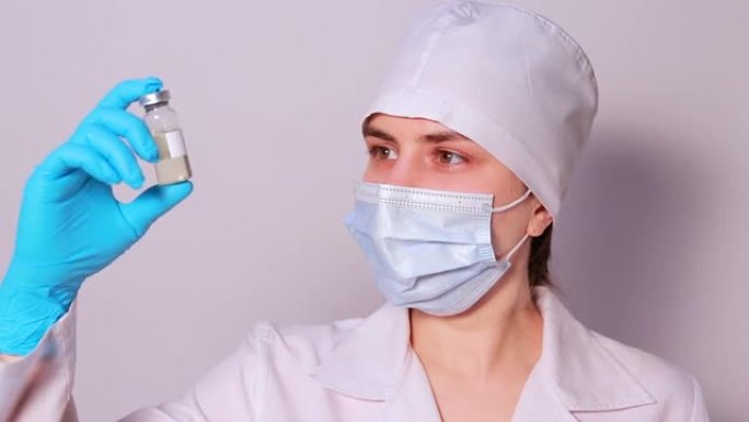 戴着医用口罩的医生或实验室技术人员将破伤风疫苗保持在白色背景上。卫生保健中疫苗接种的概念