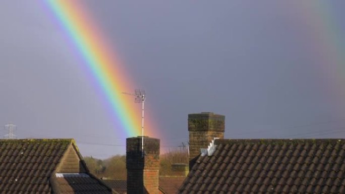 英国联排别墅屋顶和烟囱上的彩虹色彩虹，阴天