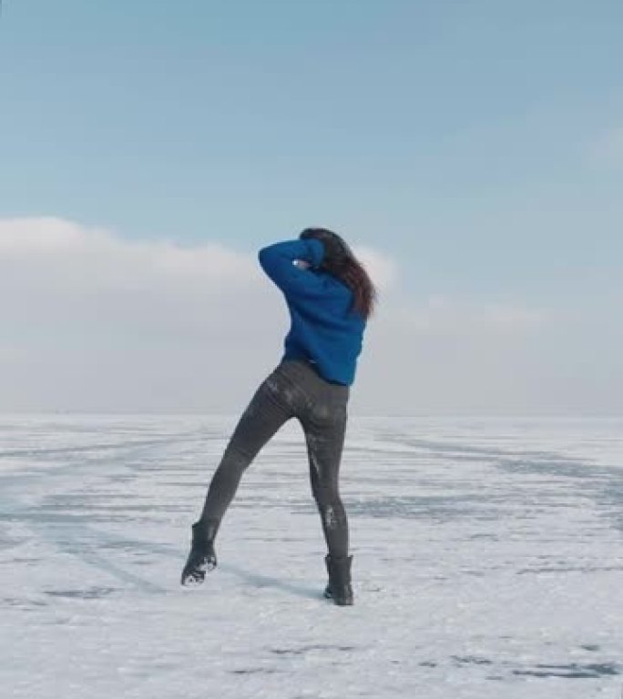 千禧一代女性职业舞者的垂直视频，在寒冷的冬天在冰冻的湖上跳舞充满活力的爵士放克或嘻哈。女性潮人在冰雪
