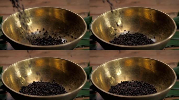 旧木桌上的整块和磨碎的黑胡椒倒在碗里。胡椒品种。磨碎的黑胡椒。木质背景上的黑胡椒玉米和黑胡椒粉。特写