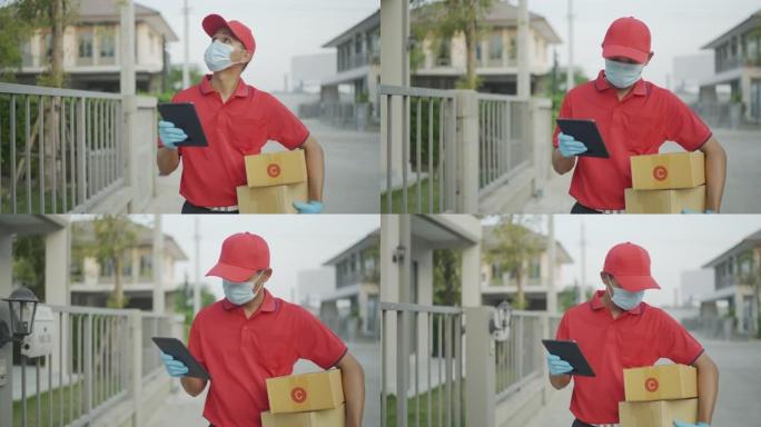 穿着红色制服的男性送货员正在寻找当前正在运送的房屋，从您持有的平板电脑中搜索门牌号。新的正常概念。