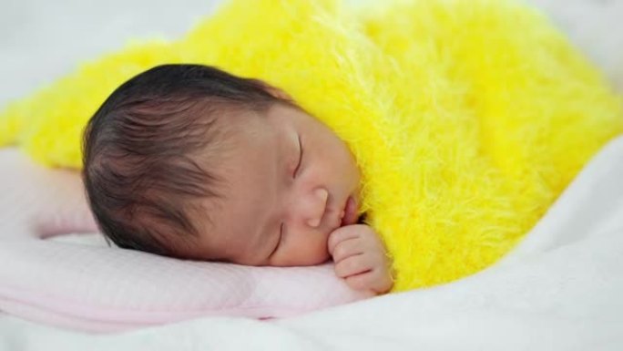 新生儿睡在床上的黄色毛毯上