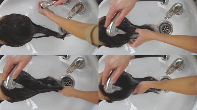理发师手上的特写镜头。主人在一家黑色美容院洗头发的女孩。