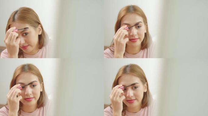 一位年轻的亚洲妇女做化妆眉刷和照镜子的特写镜头