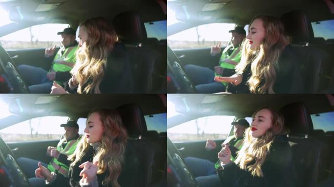 驾驶座上快乐的女人和背景汽车教练坐在车里慢动作跳舞的侧视图。轻松愉快的高加索学生和老师在阳光明媚的日