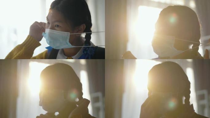 穿着制服的亚洲女学生戴着口罩靠近窗户，在被封锁后准备返回学校新型冠状病毒肺炎。新年后上学的第一天。