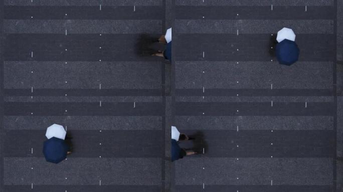 头顶俯视图夫妇路过镇广场，带着雨伞散步