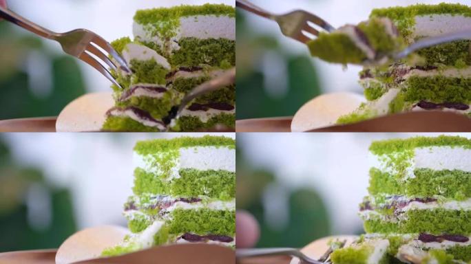 用勺子和叉子在咖啡馆里吃绿茶蛋糕，奶油和红豆。