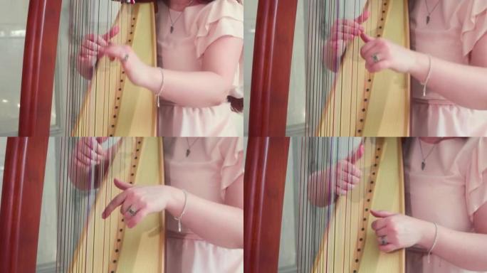 这个女孩弹竖琴。手和弦的特写