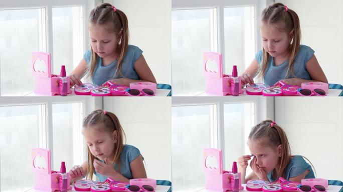 一个美丽的小女孩用蓝色的孩子画她的眼睛是阴影，照镜子。孩子在玩具美容院在家玩耍。