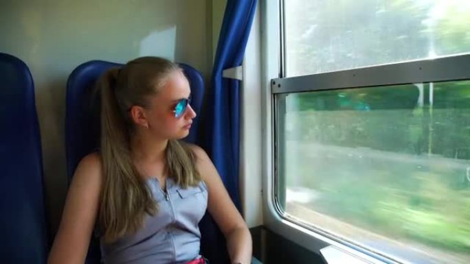戴墨镜的女孩在火车上看着窗外，笑着