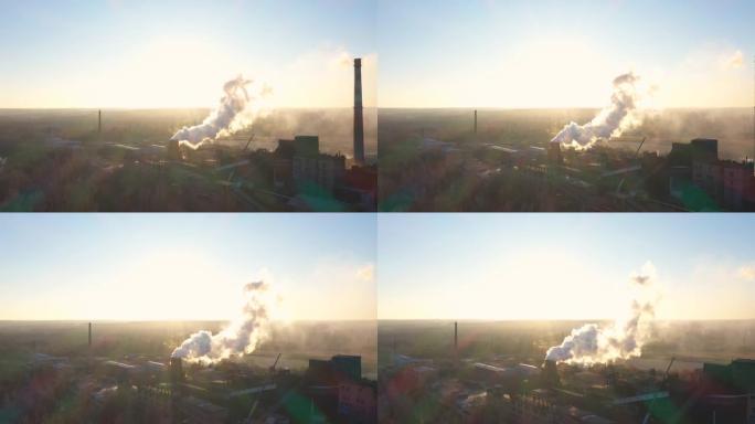植物从管道向大气中注入烟雾的鸟瞰图。无人机在工厂上方飞行，向空气中排放有毒蒸气，背景是阳光。风景秀丽