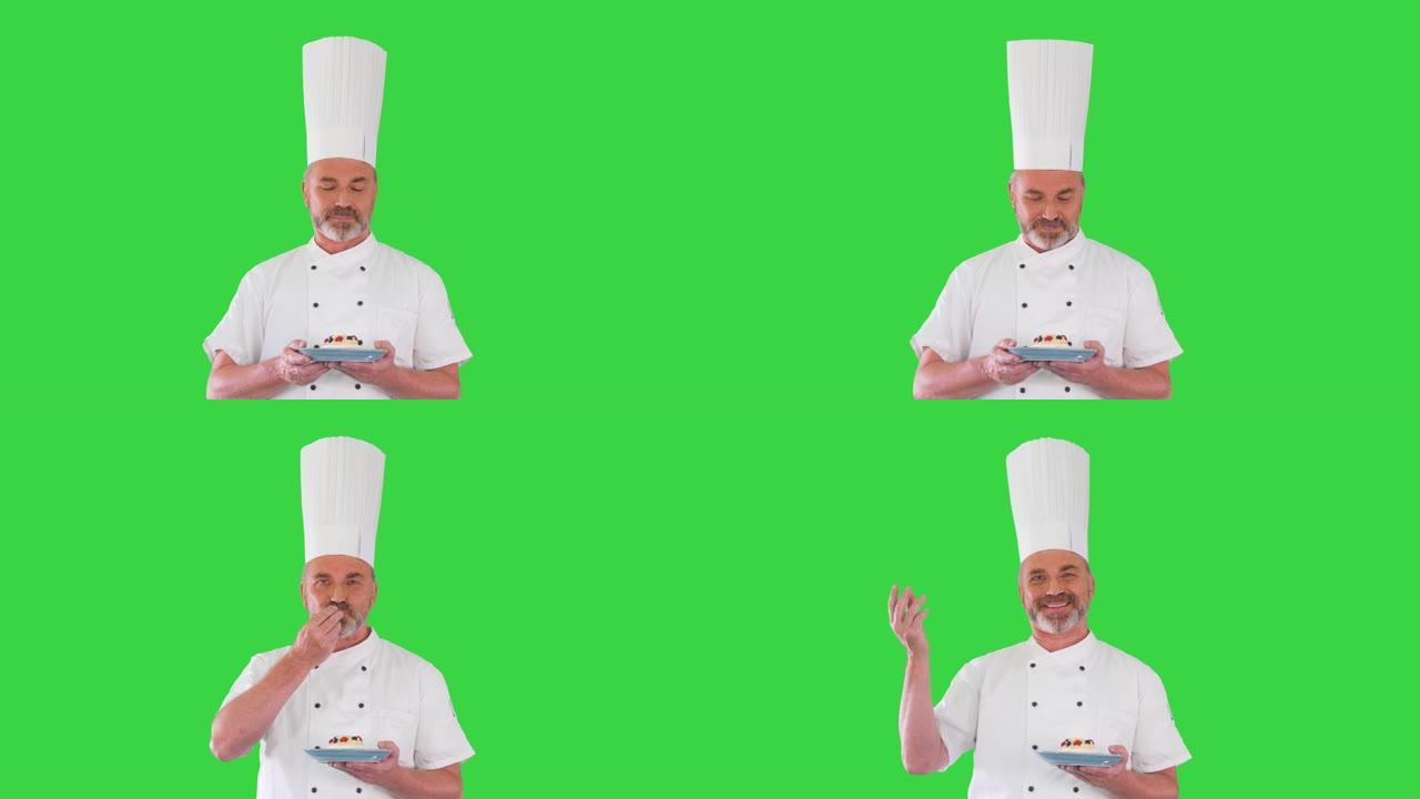大胡子男厨师厨师在绿色屏幕上用手中的甜点做出美味的手势，色度键