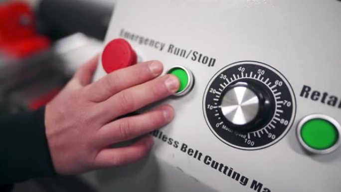 在工厂中，人手按下开始按钮的特写