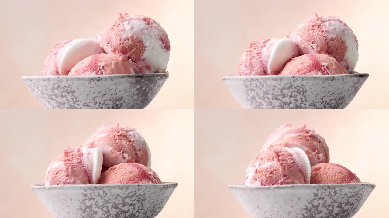 在米色背景上旋转的碗中三个粉红色水果冰淇淋球的特写