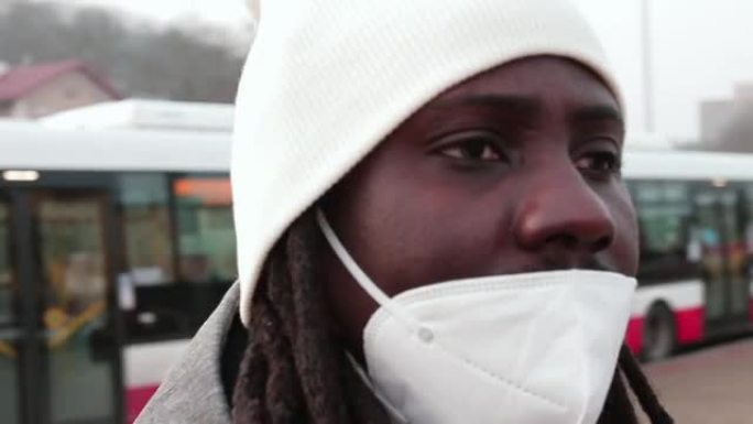 圆形肖像，一个黑人戴着白色口罩呼吸器。等待巴士站。
