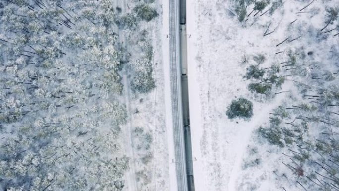 火车在积雪覆盖的冬季森林中行驶的俯视图。