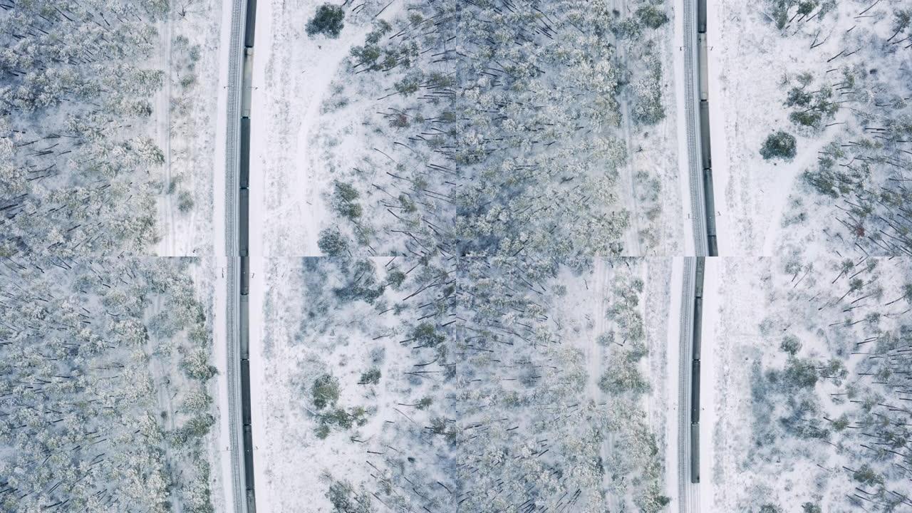火车在积雪覆盖的冬季森林中行驶的俯视图。