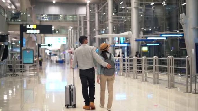 夫妇亚洲人走在机场航站楼等待登机。