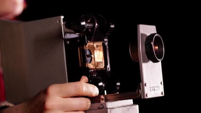 旧的幻灯片放映机的特写镜头，并手动旋转带有图片的移动胶片的轮子