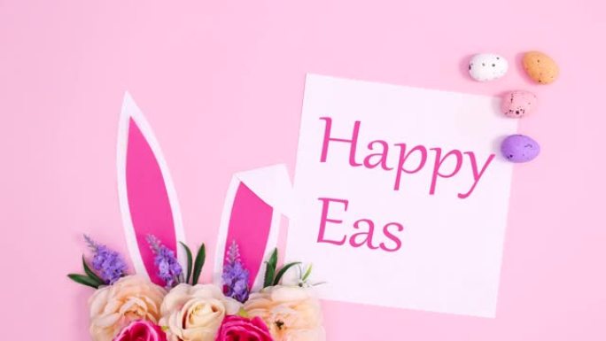 复活节快乐用兔子耳朵写在纸上，在柔和的粉红色背景上绽放花朵。停止运动