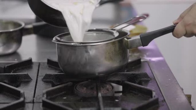 SLO MO: 厨师关闭煤气并过滤椰奶汤中的成分。