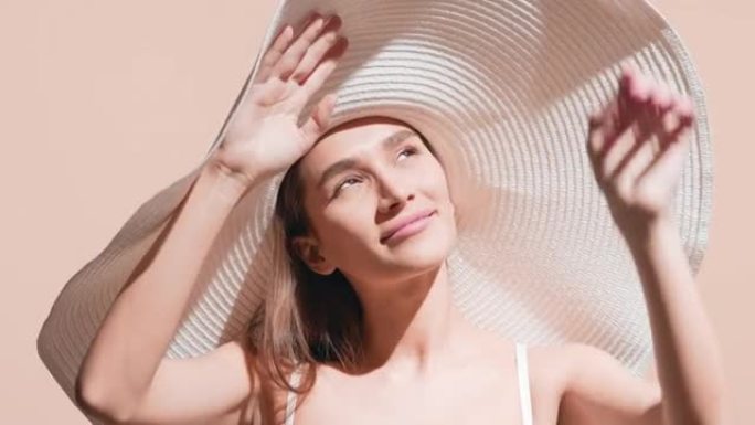 戴着大帽子的女模特用手掌遮住太阳的脸