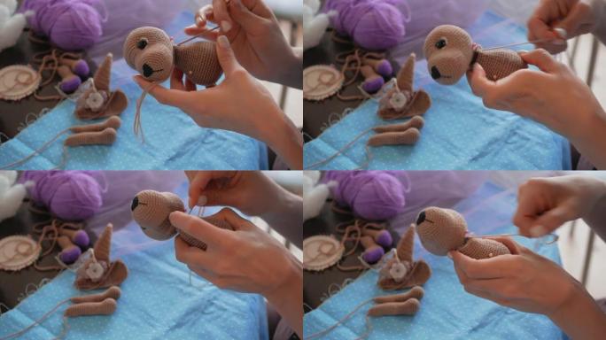 编织amigurumi玩具狗的年轻女子。缝在玩具头上。特写