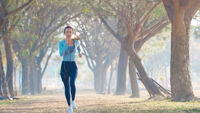 美丽的年轻女子早上在公园跑步