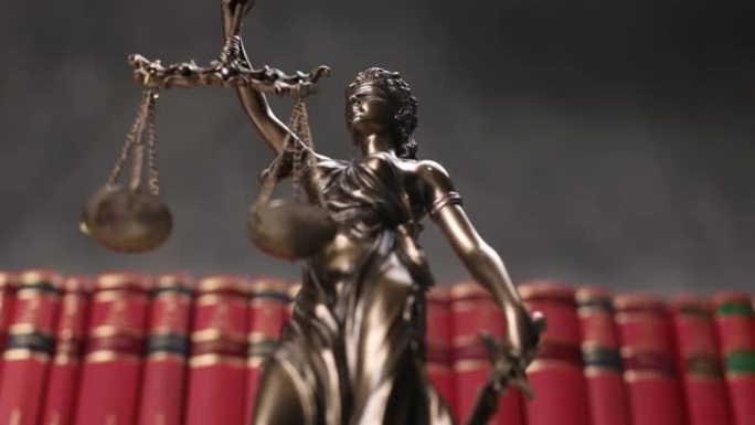 以蒙眼女神为代表的铜制法律雕像，旋转着保持平衡，象征着公正和两大法律来源，以书籍为背景