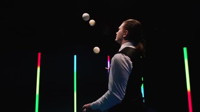 轨道射击专业马戏团表演者在明亮的霓虹灯下在黑色工作室背景下用五个白球杂耍。特写。慢动作