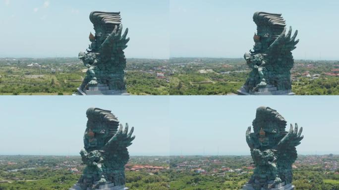 在印度尼西亚巴厘岛环绕鹰航Wisnu Kencana雕像的空中射击。背景为居民区的著名宗教雕像