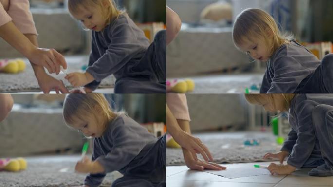 妈妈和女儿一起玩，教如何画画。感兴趣的金发蹒跚学步