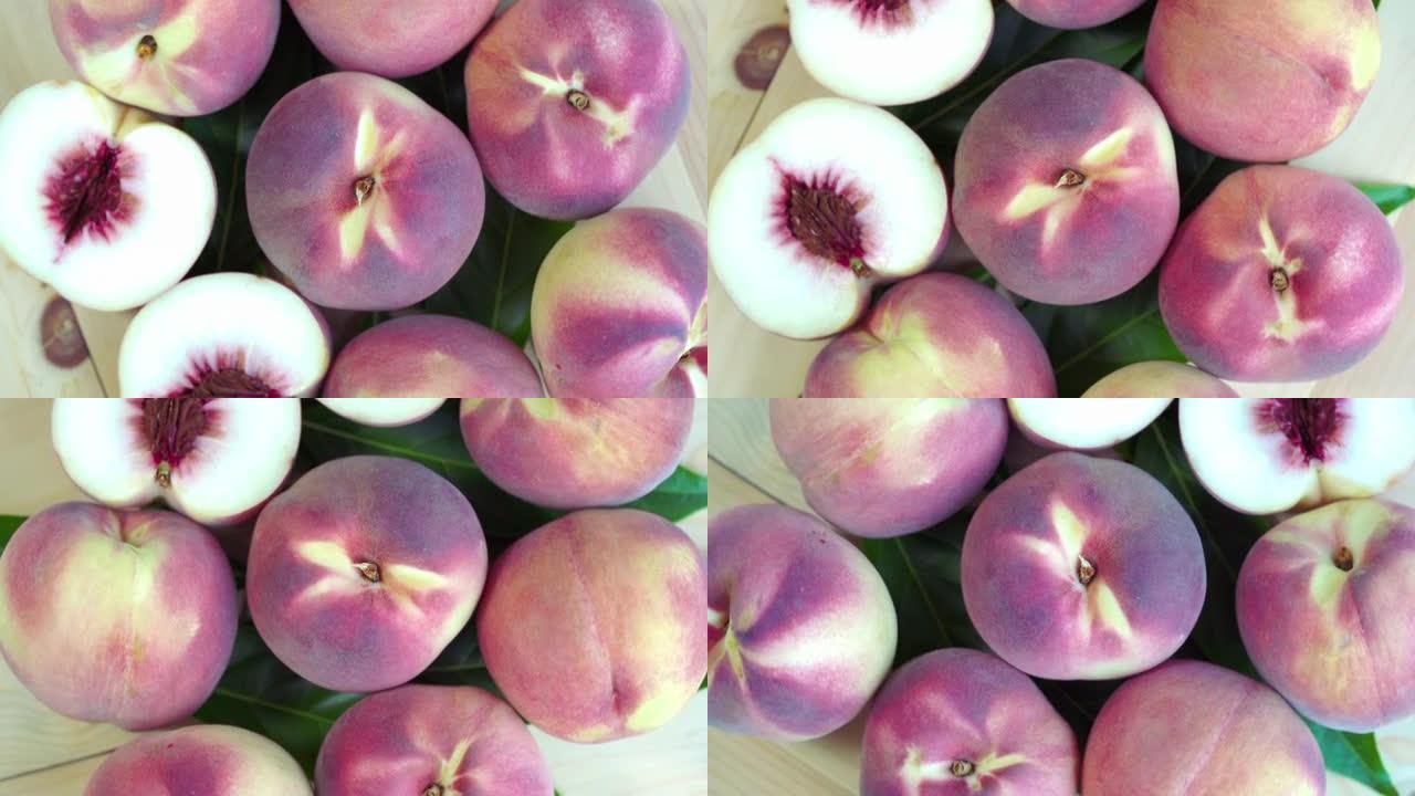 俯视图旋转新鲜桃子与切片特写，桃子水果放在花园的木桌上。