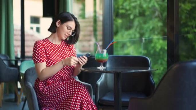 快乐的女人坐在酒吧里，用智能手机自拍