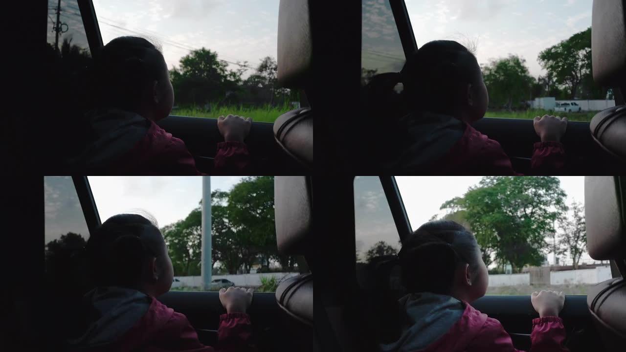 4k亚洲小女孩在车外看东西。早上，女孩在去学校的路上看着车窗外的东西。孩子们从车里看到街景放松。汽车