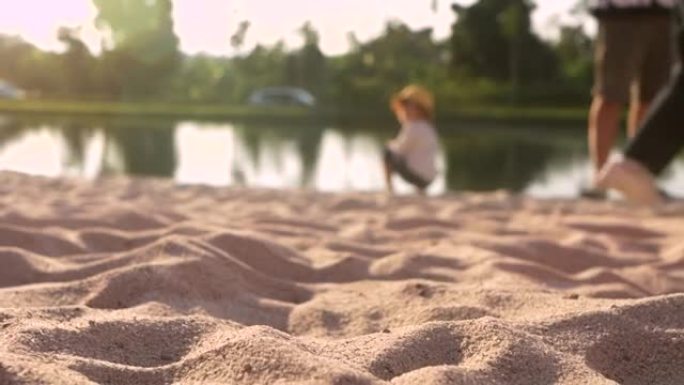 在一个小女孩坐在沙滩上的背景下，白色细沙的特写。选择性聚焦。