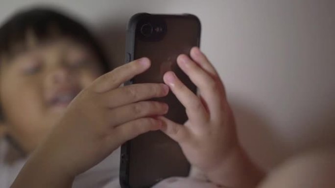 亚洲小孩晚上在卧室的床上使用智能手机