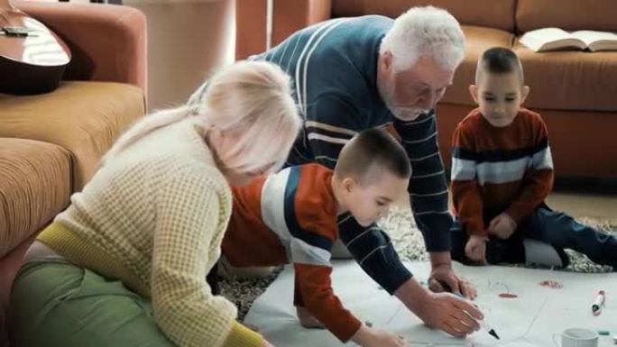 高级祖父在一张大纸上为他的孙子孙女画太阳。与祖父母在地板上玩耍，绘画，着色，空闲时间和家庭聚会的双胞