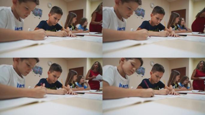 两个年轻的男生在小学教室里的笔记本上写字