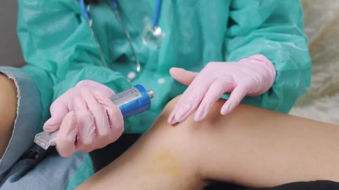 一名戴着医用手套的护士在一名女性患者受伤的膝盖上摩擦药膏。