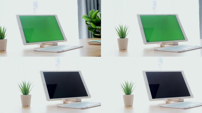 绿色屏幕数字平板电脑，键盘和电脑鼠标放在家里靠近窗户的桌子上，技术概念。