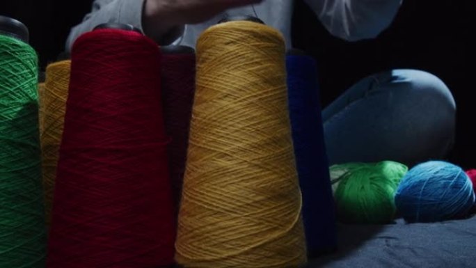 Female hands are winding yarn up to a ball