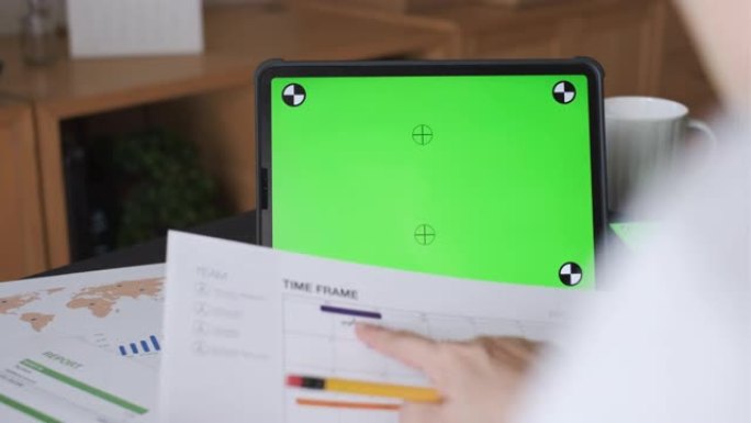 绿色屏幕，亚洲女性在家中使用平板电脑进行视频电话会议。新的正常办公室生活概念。技术设备上的绿色屏幕