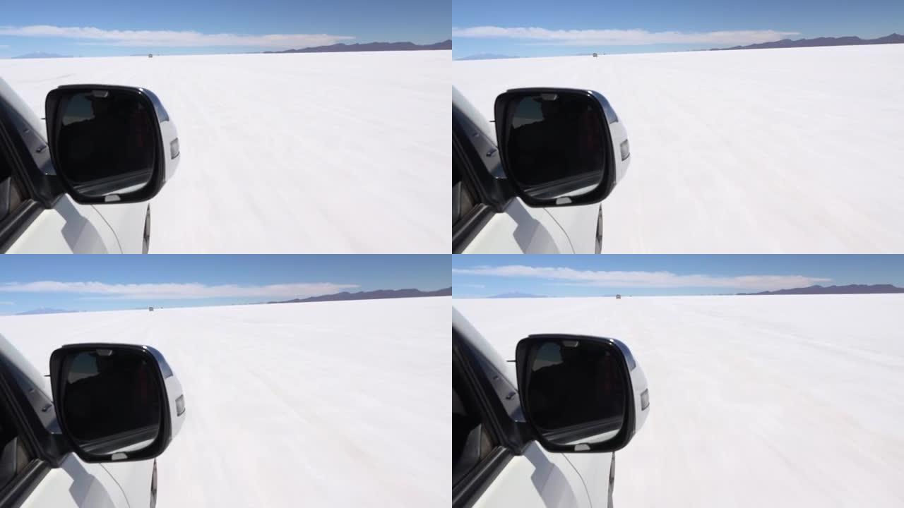 在沙漠中驾驶吉普车在明亮的水晶盐表面行驶。前景的后视镜。