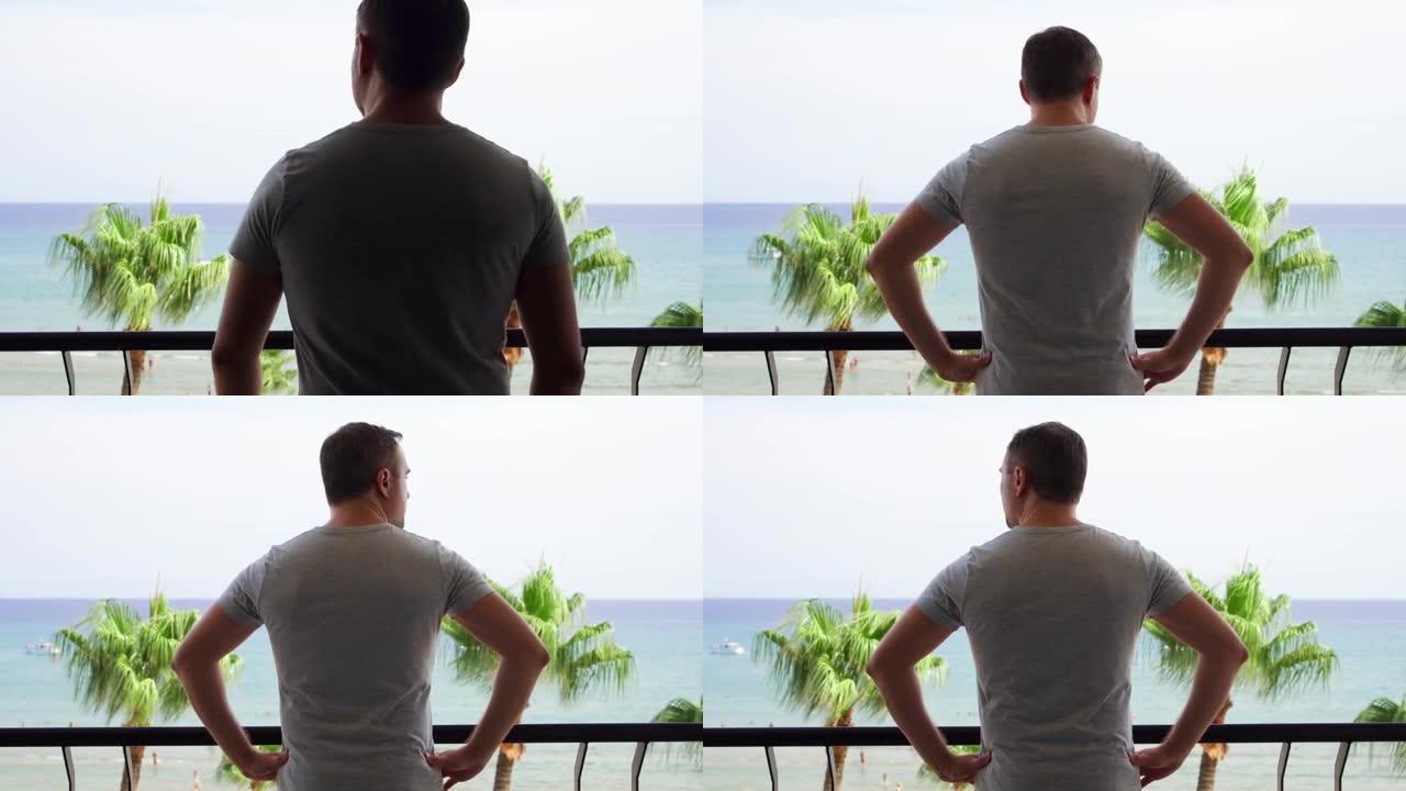 男人走到阳台上，从露台上欣赏风景。度假的男性看地中海