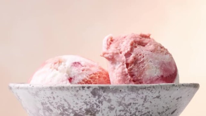 灰色陶瓷碗中两个粉红色草莓冰淇淋球的特写放大
