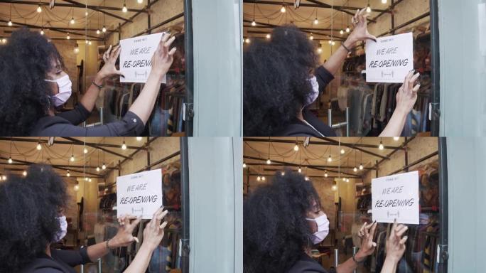 一名混血女商人的慢动作视频，她在商店的门上贴上重新开业的标志